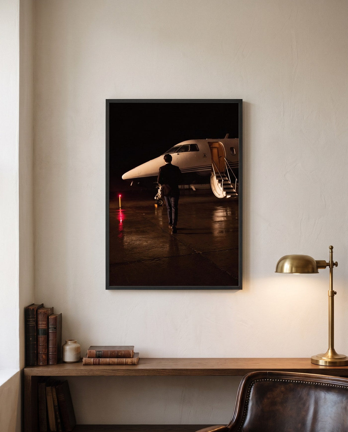 A framed print from the IMPERO series on a study wall, brass lamp and leather chair