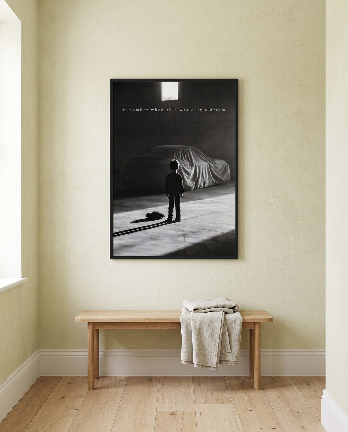 A framed print from the L'INIZIO series in a bright hallway above an oak bench